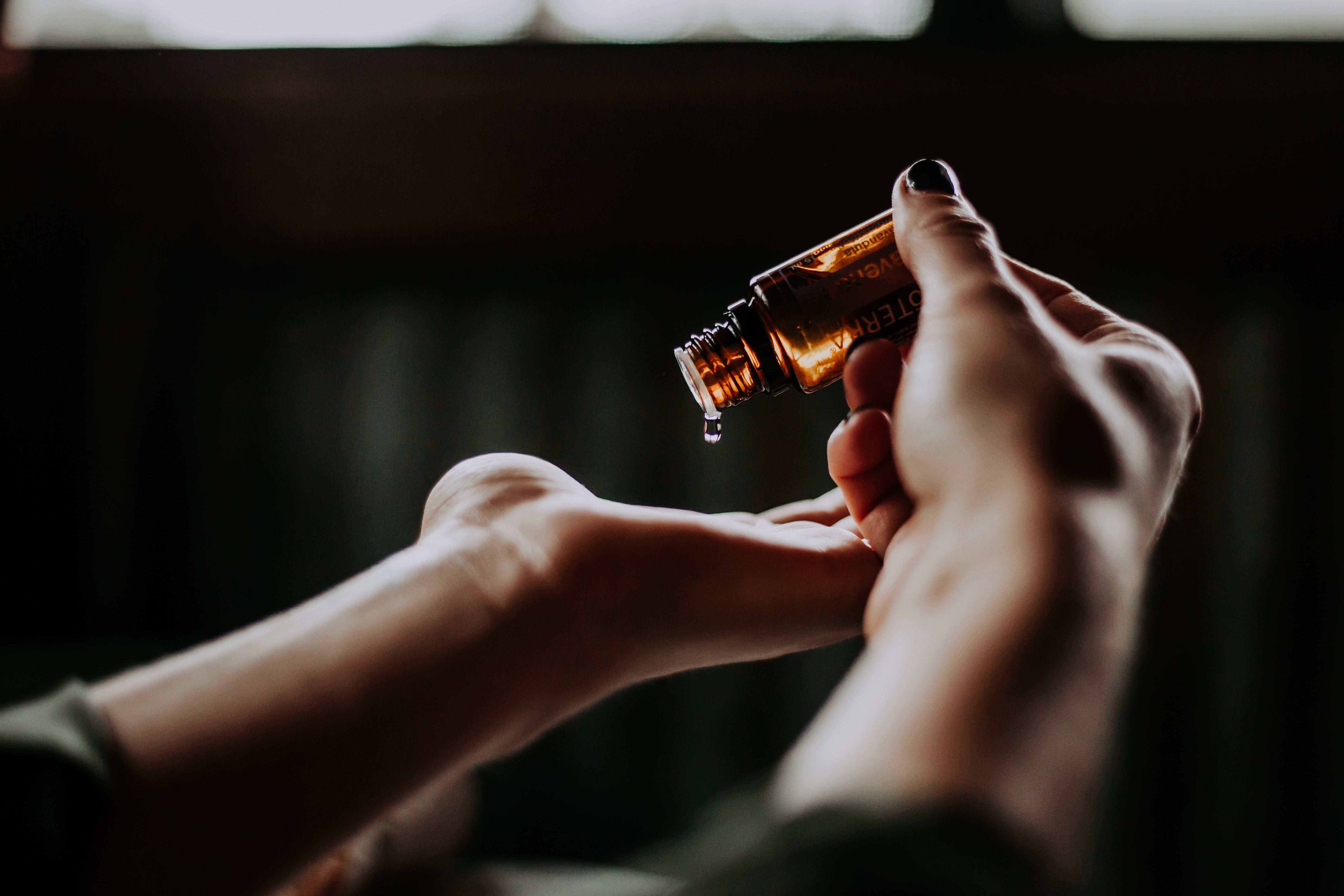 hands pouring liquid out of a medicine bottle.